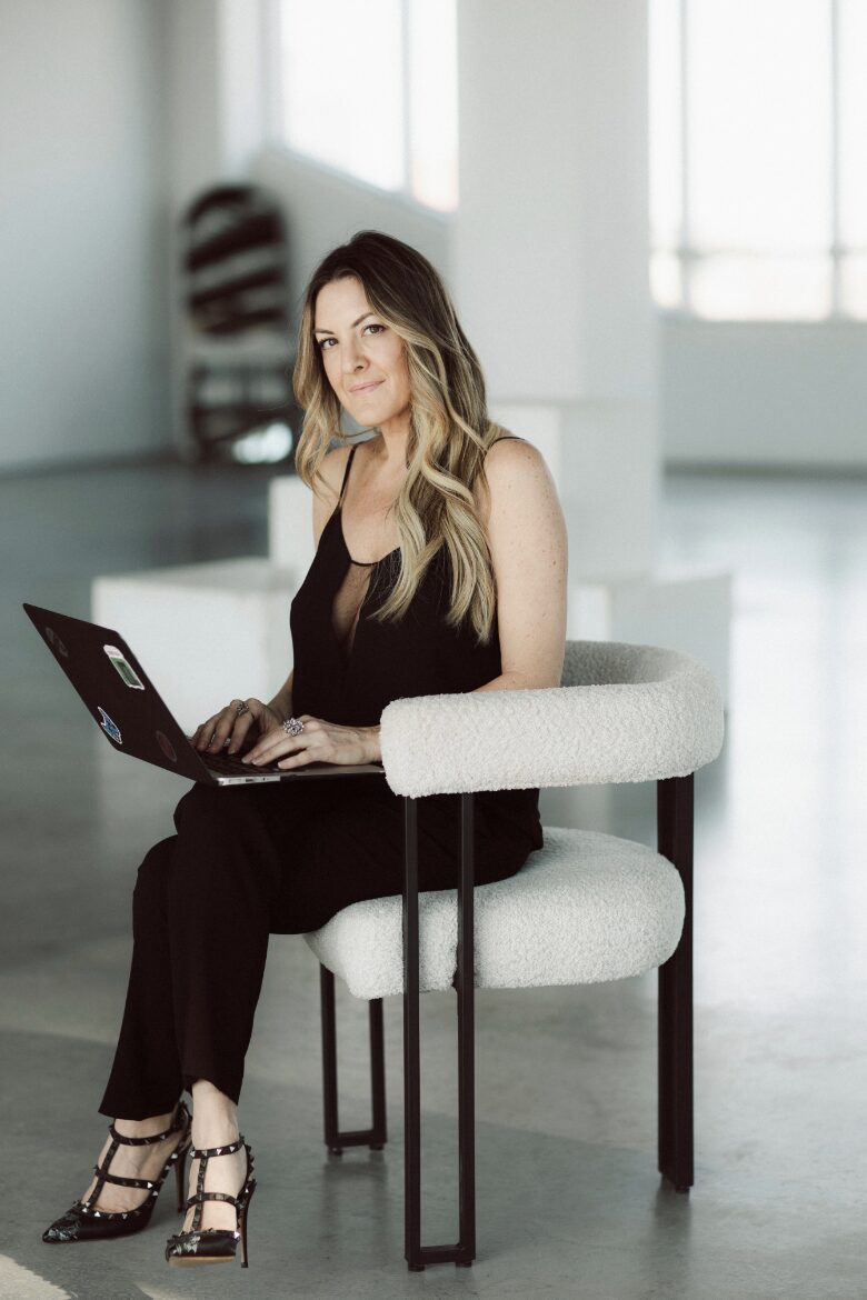 Mackenzie Archibald, RSW, seated with her laptop in a sunlit studio.